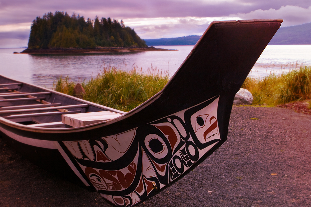 A native canoe on a beach near coastal waters.