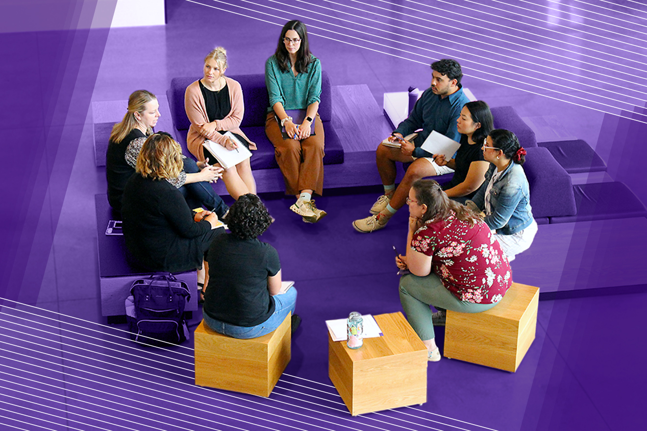 Photograph of a group of people sitting in a circle on large wooden cubes