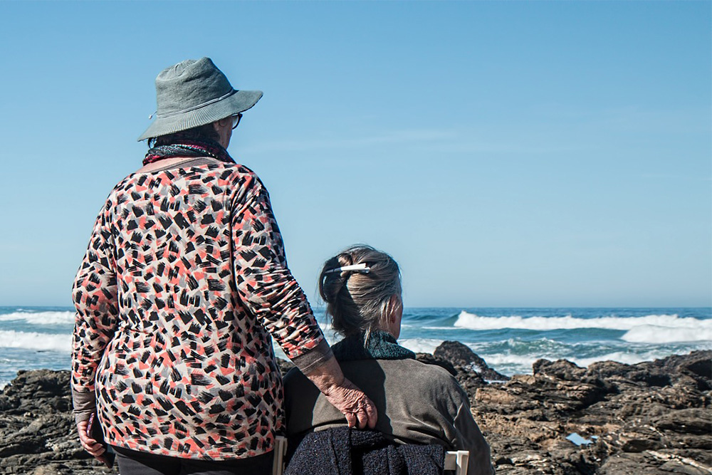 Photograph of two women looking at ocean waves.