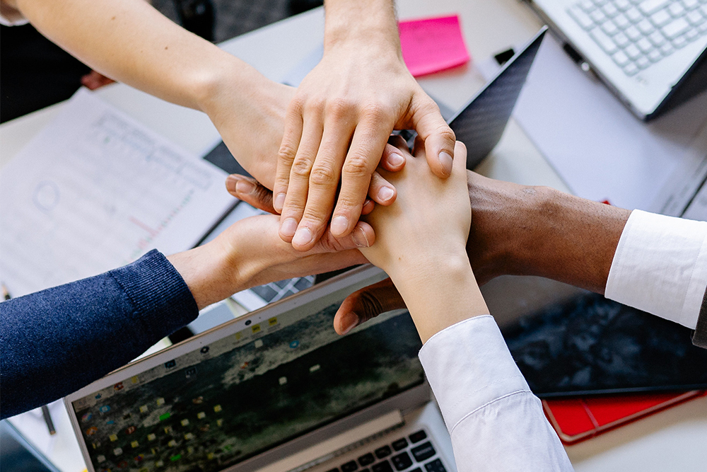 Five people join hands to celebrate teamwork