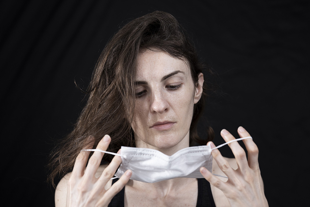 Photograph of a person looking at a cloth face mask in their hands.